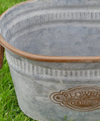 Metal bucket with 'Flower Garden' branding on grass