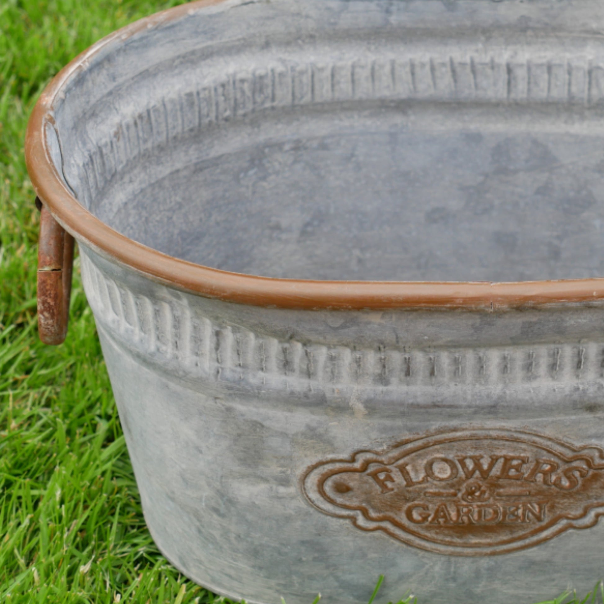 Metal bucket with 'Flower Garden' branding on grass