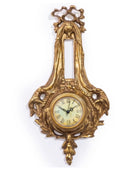 Decorative gold wall clock with intricate designs on a white background