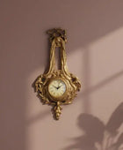 Decorative gold wall clock on a pink wall with plant shadows