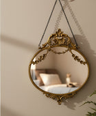 Decorative gold mirror with intricate designs on a white wall.