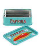 A turquoise metal Paprika chili pepper tin with its lid placed in front. The tin features the brand name 'PAPRIKA' in red with black text underneath reading 'SUN GROWN • FRESHLY GROUND'.