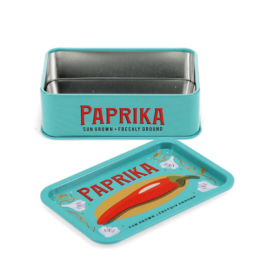 A turquoise metal Paprika chili pepper tin with its lid placed in front. The tin features the brand name 'PAPRIKA' in red with black text underneath reading 'SUN GROWN • FRESHLY GROUND'.