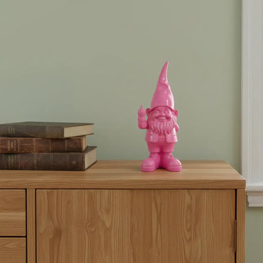 Pink gnome figurine on a wooden surface with books against a green wall.
