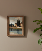 A framed landscape painting hanging on a beige wall, styled next to a green houseplant with sunlight casting shadows across the wall.