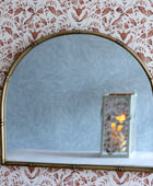 Gold-framed mirror on a wall with floral wallpaper