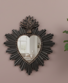 Decorative heart-shaped mirror with intricate design on a beige wall.
