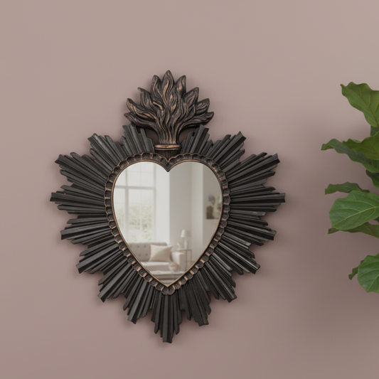 Decorative heart-shaped mirror with intricate design on a beige wall.