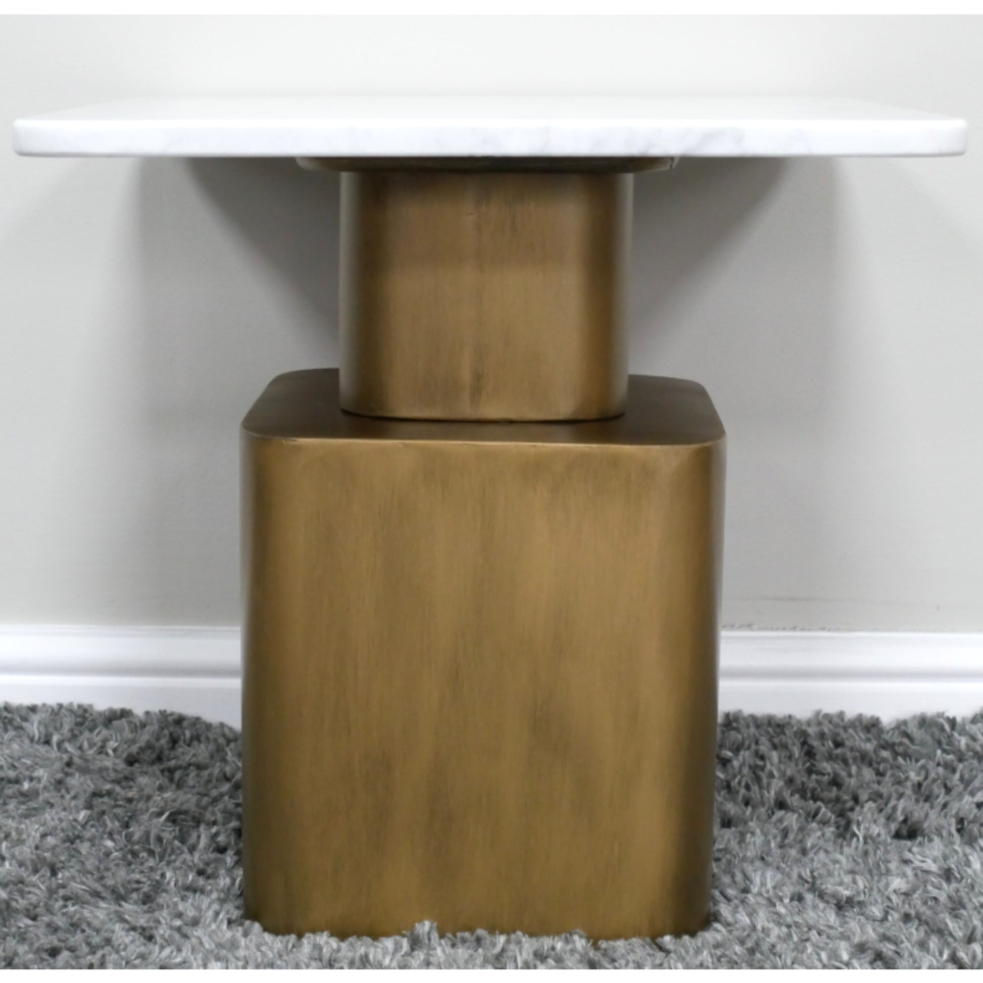 Close-up of a table with a gold metal base on a gray carpet.