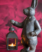 Statue of a rabbit holding a lantern against a red background