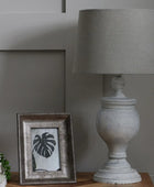 Decorative lamp and framed picture on a wooden surface with a neutral background
