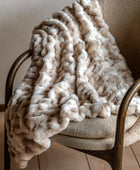 Beige textured blanket draped over a chair in a warm-toned room.