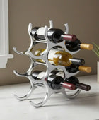 Silver wine rack holding multiple bottles on a white surface with a neutral background