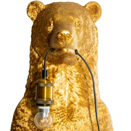 Gold bear-shaped lamp with a visible light bulb on a white background