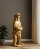 Gold bear-shaped floor lamp in a room with a plant and curtains.