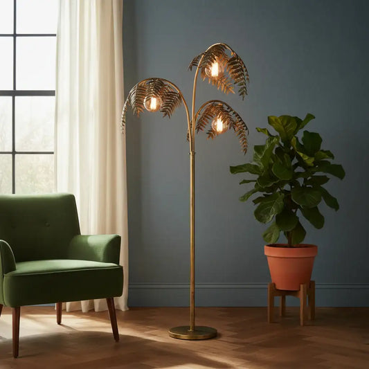 Gold leaf floor lamp in a room with a green chair and potted plant.