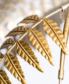 Gold leaf-patterned metal design on a white background