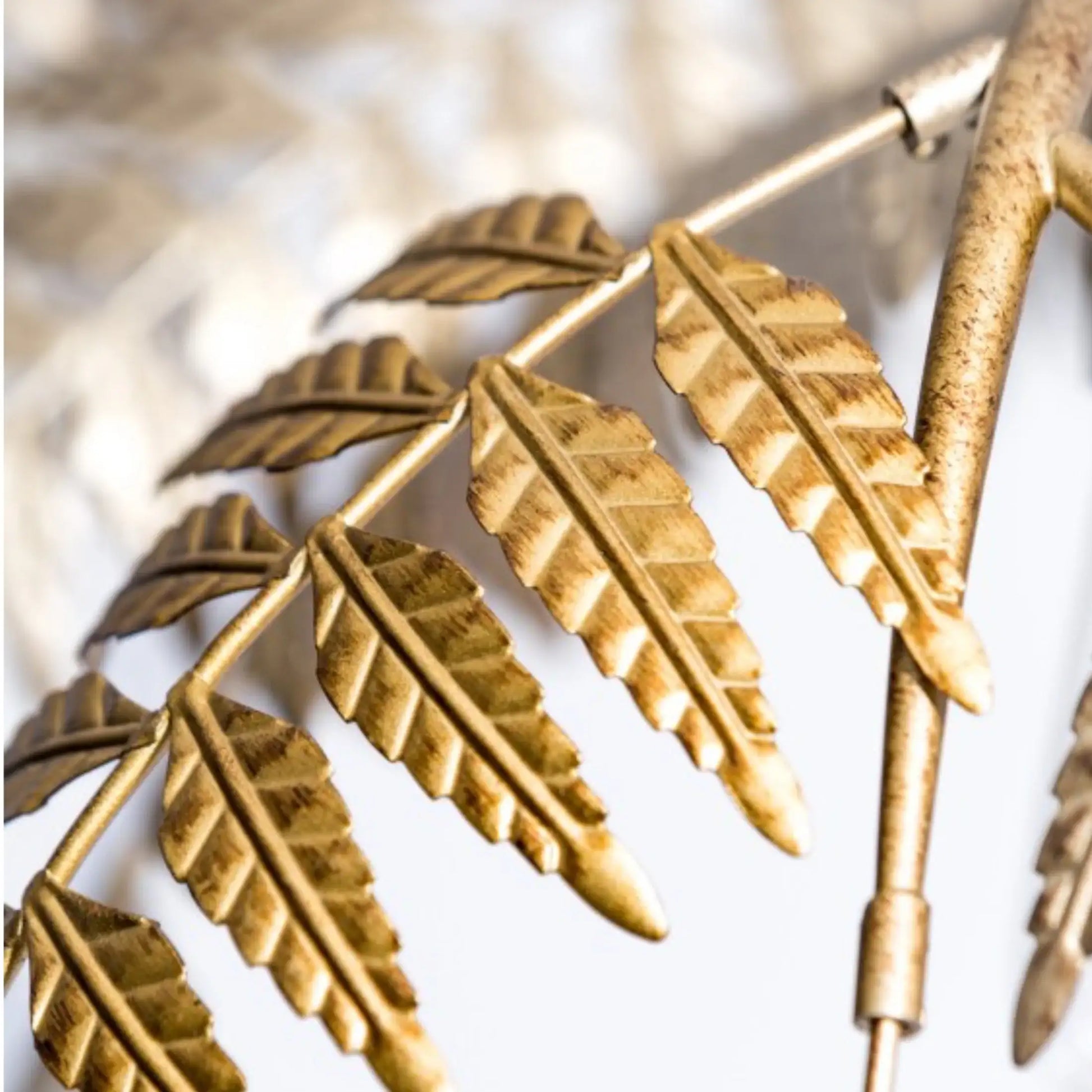Gold leaf-patterned metal design on a white background