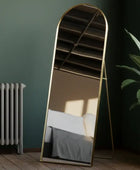 Arched floor mirror with gold frame in a room setting