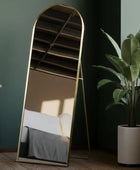 Gold-framed mirror leaning against a wall with a plant nearby