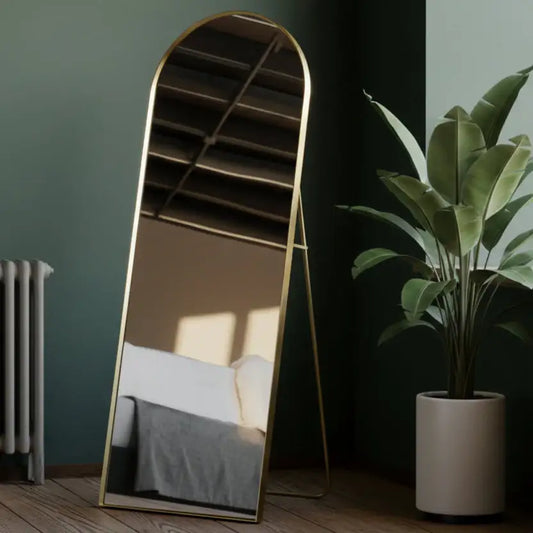 Gold-framed mirror leaning against a wall with a plant nearby