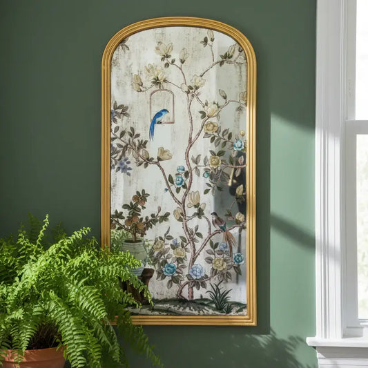 Decorative mirror with floral and bird design on a green wall