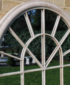 Round window with decorative iron grille in a stone wall setting