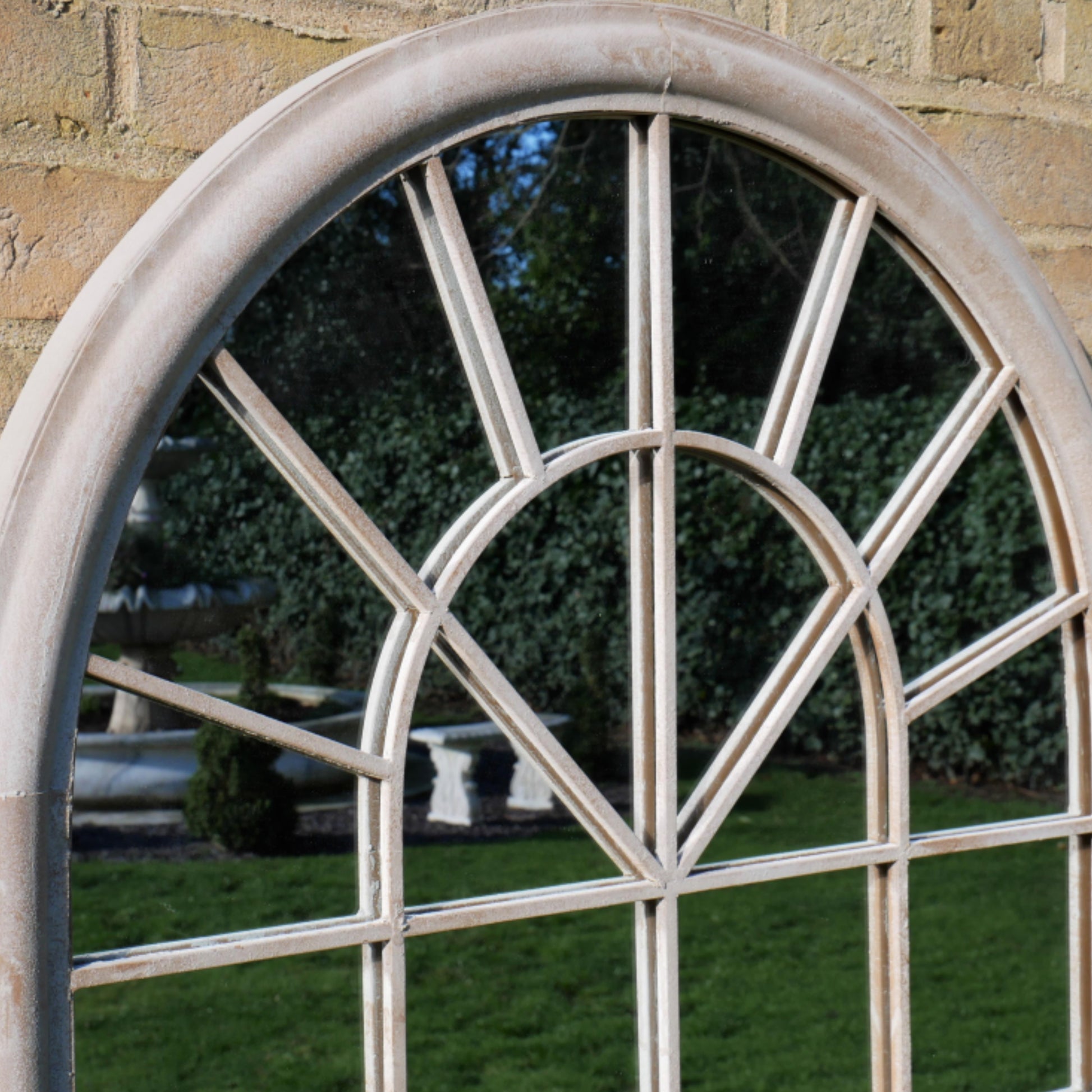 Round window with decorative iron grille in a stone wall setting