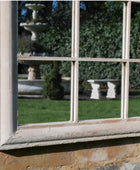 Reflective window on a stone wall with garden reflections