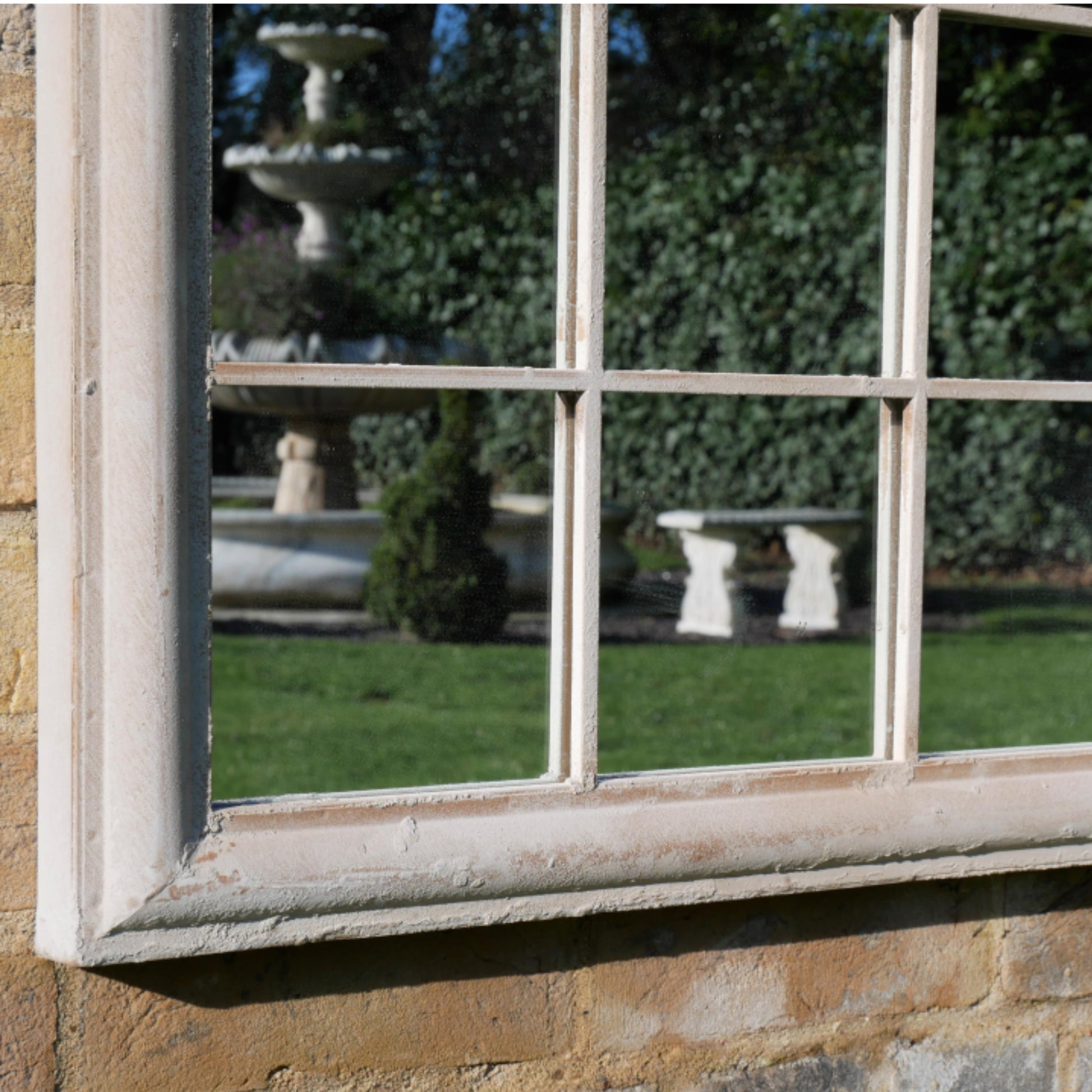 Reflective window on a stone wall with garden reflections