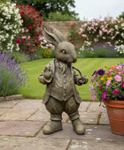 Statue of a rabbit in a garden with flowers and plants