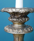 Decorative silver candle holder with a white candle against a blue background