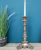 Decorative candlestick with a candle on a wooden surface against a blue wall