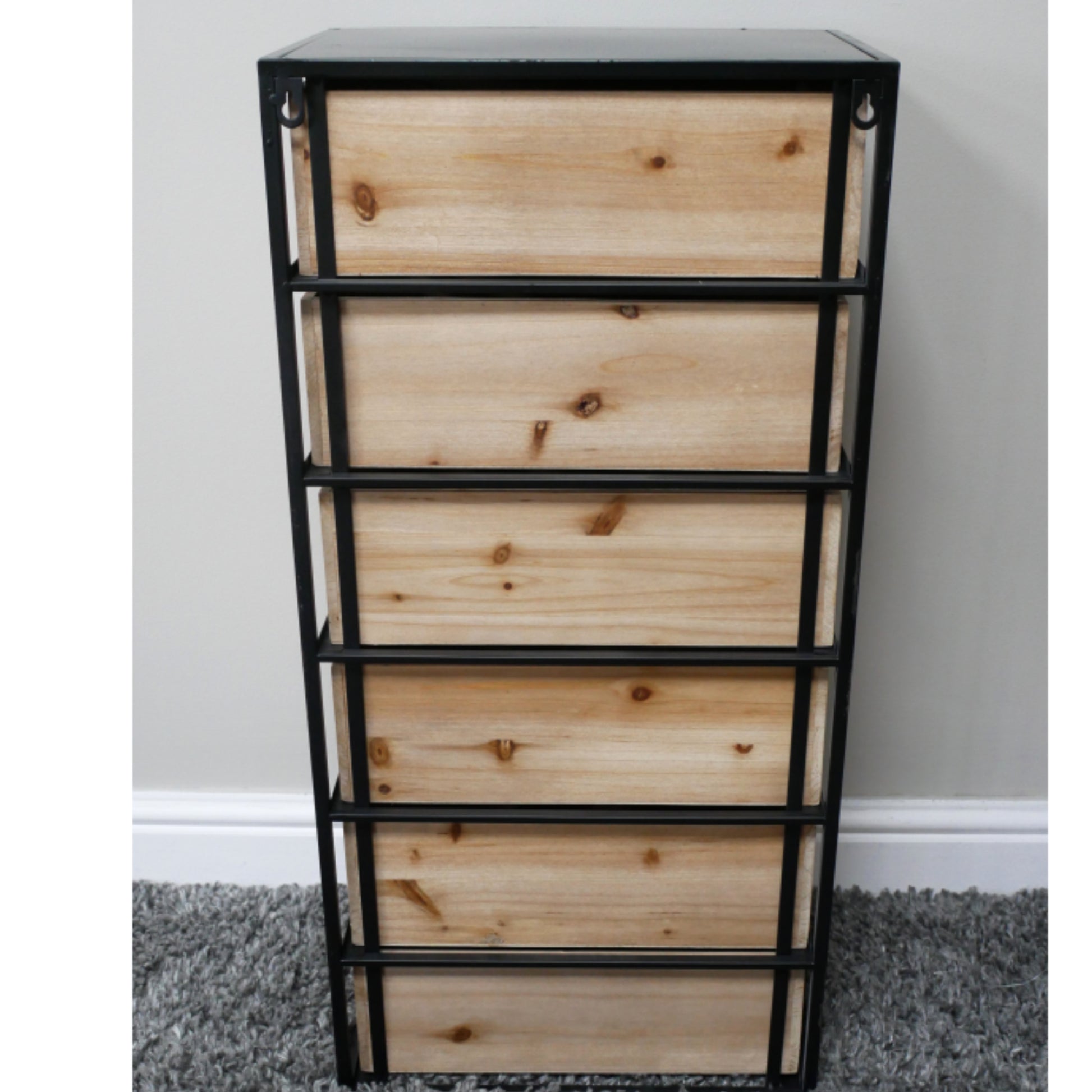 Wooden drawer unit with metal frame against a gray wall