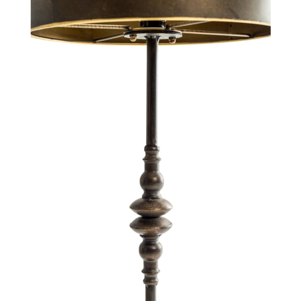 A close-up of a floor lamp with a dark metal turned-wood style stem, a drum shade, and a warm brass-toned inner lining, shown against a plain white background.