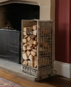 Wooden firewood basket filled with logs next to a fireplace.