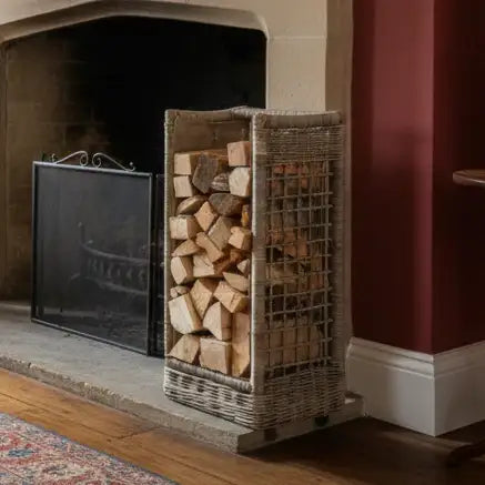Wooden firewood basket filled with logs next to a fireplace.