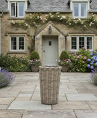 Cottage with decorative flowers and a wicker basket on a stone patio