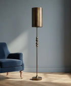 Blue armchair and standing lamp in a room with a window and plant