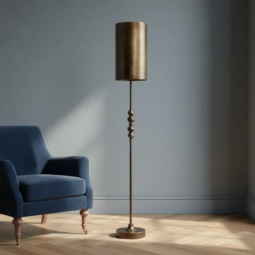 Bronze floor lamp next to a blue armchair in a room with a gray wall.
