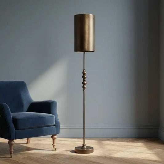 Bronze floor lamp next to a blue armchair in a room with a gray wall.