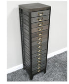 Tall metal drawer unit with grid design on a gray carpeted floor against a white wall.