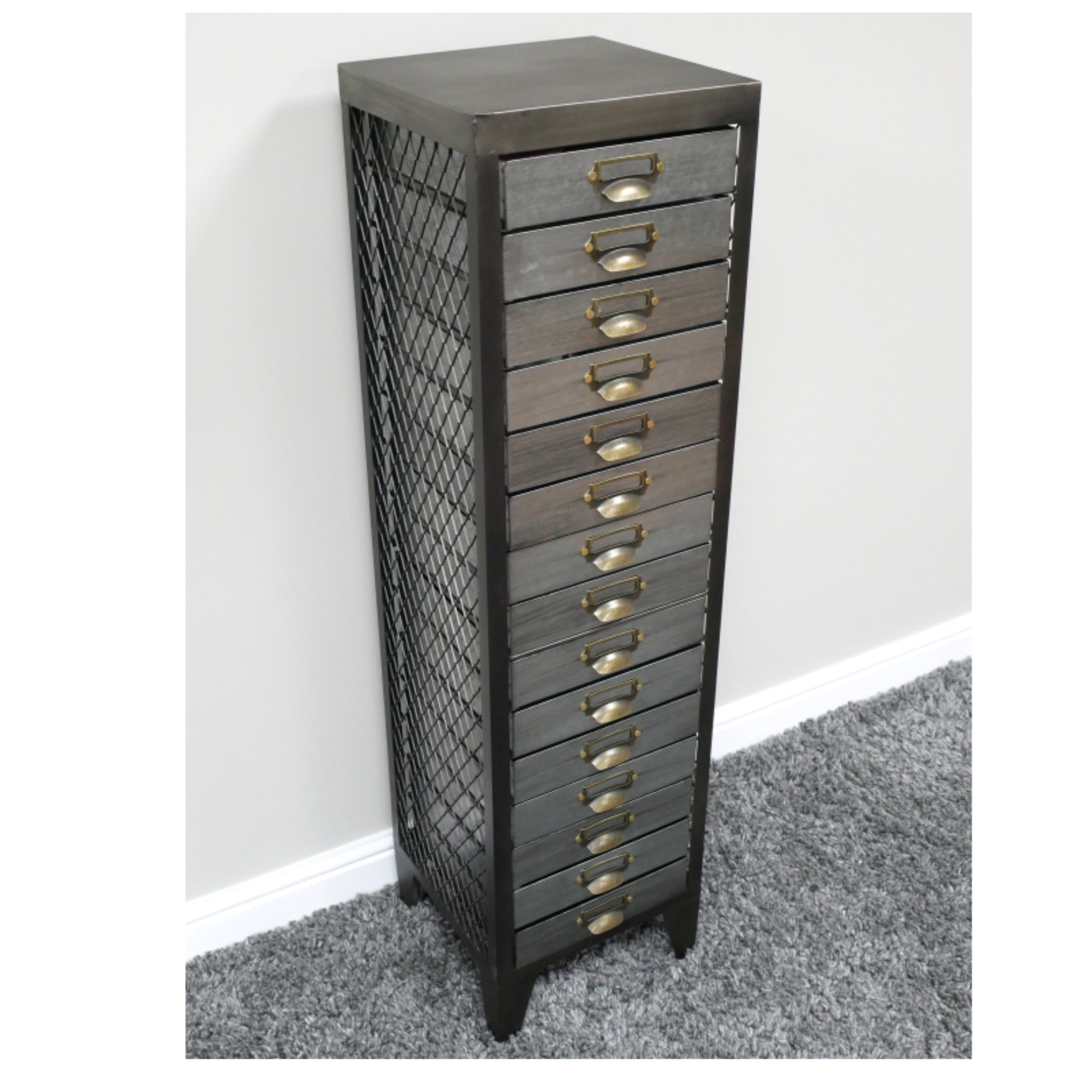 Tall metal drawer unit with grid design on a gray carpeted floor against a white wall.