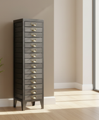 Tall gray jewelry cabinet with multiple drawers in a room with a plant and large window.