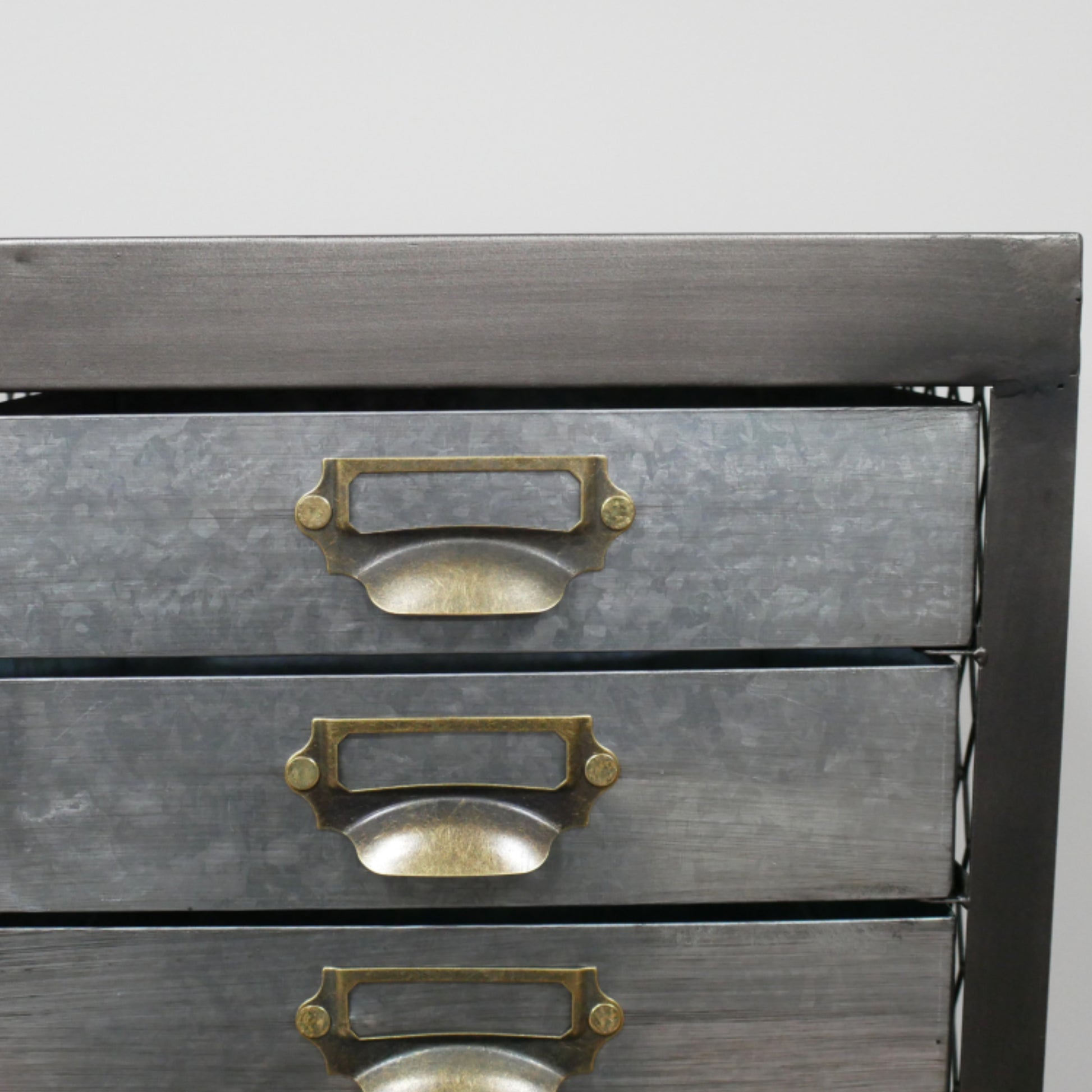 Metallic drawer unit with brass handles on a gray background