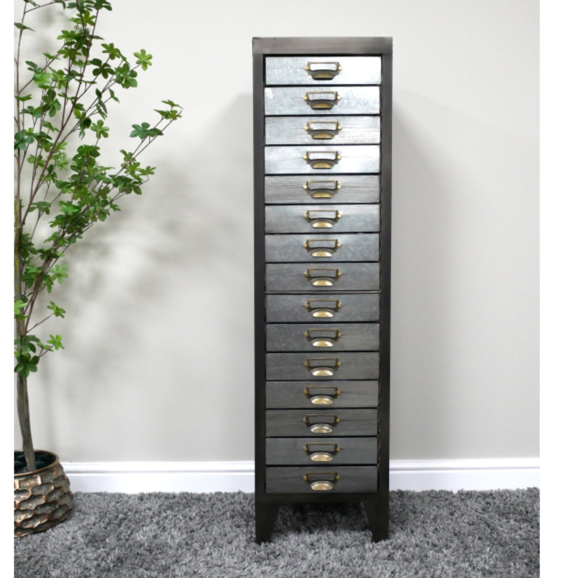 Tall gray dresser with multiple drawers against a white wall.