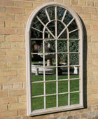 Arched window-style mirror on a brick wall