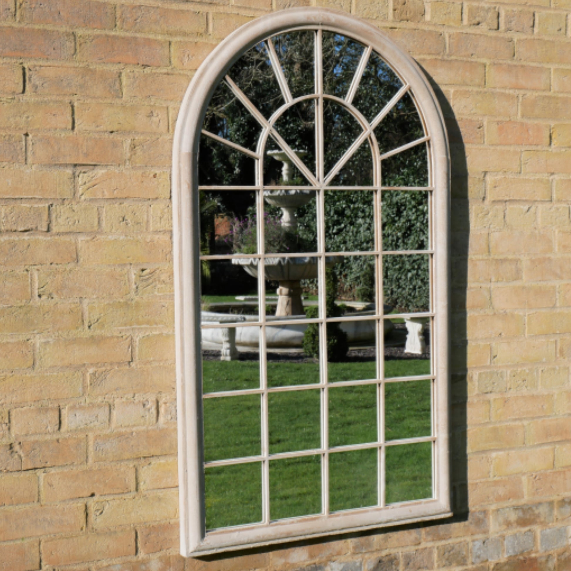 Arched window-style mirror on a brick wall