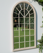 Arched window mirror on a white wall with greenery