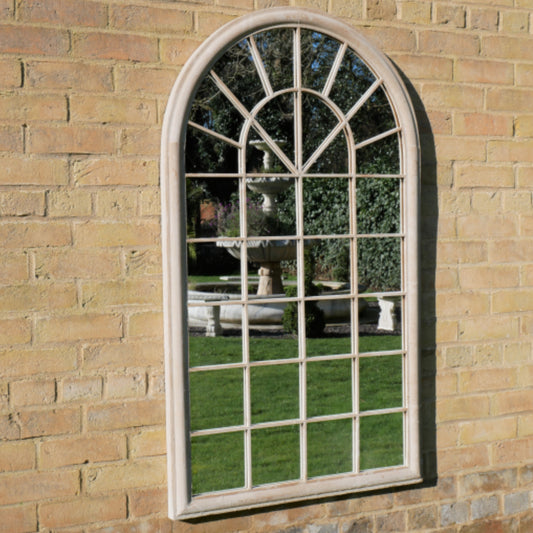 Arched window-style mirror on a brick wall